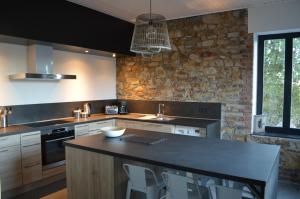 a kitchen with a black counter and a stone wall at Gite Terre de ciel in Ferrières