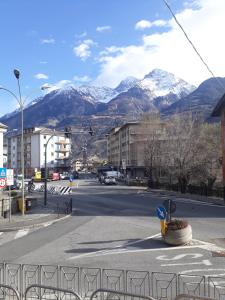 an empty street with snow capped mountains in the background at Aosta Romana case vacanza in Aosta