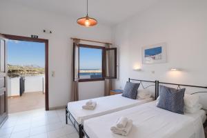 two beds in a room with a view of the ocean at Aphrodite White Studios Lindos in Lindos