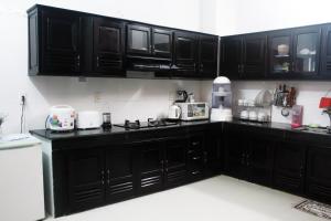 a kitchen with black cabinets and white appliances at Hana Homestay Danang in Danang