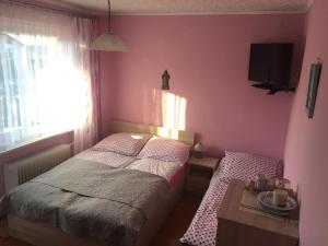 ブワディスワボボにあるPokoje gościnne "Przy Parku"のピンクの壁のベッドルーム(ベッド1台、テーブル付)