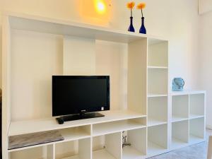 a tv on a white shelf in a room at Front Lake Apartment Bardolino in Bardolino