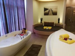 a woman sitting in a bath tub in a bedroom at Rio Stava Family Resort & Spa in Tesero