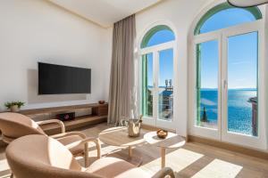 ein Wohnzimmer mit einem TV und großen Fenstern in der Unterkunft OLA Opatija Luxury Apartments in Opatija