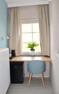 a desk with a blue chair and a window at B&B Villa Verde in De Haan
