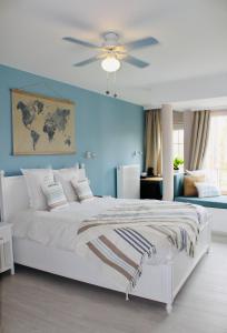 a bedroom with a white bed with a blue wall at B&B Villa Verde in De Haan