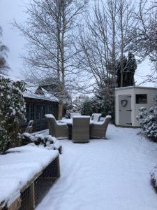 un patio cubierto de nieve con sillas y mesas en Truffle Lodge, en Lindfield