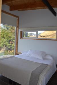 a bedroom with a white bed and a window at Cabañas Patagonia Indómita in Coihaique