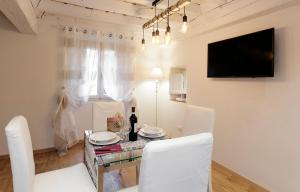 ein Esszimmer mit einem Tisch mit weißen Stühlen und einem TV in der Unterkunft Tornabuoni - Flo Apartments in Florenz