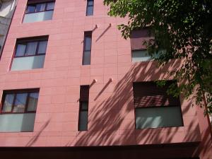 un edificio de ladrillo rosa con ventanas y un árbol en Apartamento Cifuentes, en Granada