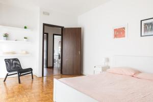 biała sypialnia z łóżkiem i czarnym krzesłem w obiekcie Cappuccino 36 House in Venezia w Mestre