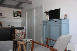 a living room with a blue cabinet with a tv on top at Au Coin des Cerisiers in Montclus