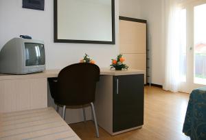 Habitación con escritorio, TV y silla. en Hotel Al Fogo en Bevazzana