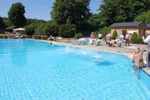 une grande piscine bleue avec des personnes assises autour de celle-ci dans l'établissement Ferienwohnungen mit Wellnessoase im Luftkurort Altenbrak, à Altenbrak