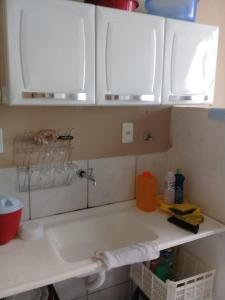 a kitchen counter with white cabinets and a sink at Seu Apartamento em Itaúna in Itaúna