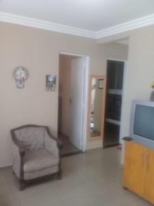 a living room with a chair and a television at Seu Apartamento em Itaúna in Itaúna