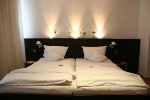 ein großes weißes Bett mit einem schwarzen Kopfteil und weißen Kissen in der Unterkunft Hotel Lorenz in Essen
