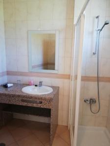 a bathroom with a sink and a shower with a mirror at Rossio Sol Mar in Lagos