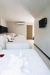 a row of white beds in a room at The Aqua Kohphangan in Haad Rin