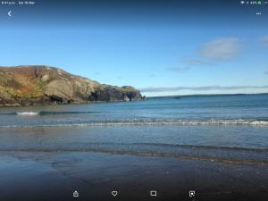 a beach with the ocean and a rocky coastline at Church Street Cottage in Rosscarbery