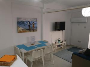ein Wohnzimmer mit einem Tisch und Stühlen sowie einem TV in der Unterkunft Bettys 1br seafront apt in Larnaka