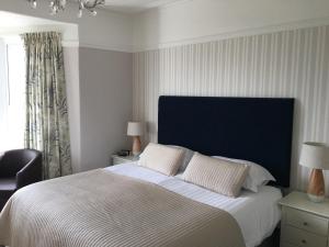 a bedroom with a large bed with a blue headboard at Woodlands Guest House in Saundersfoot