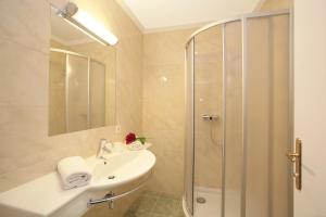 a white bathroom with a shower and a sink at Gasthof zur Post in Maishofen