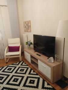 a living room with a flat screen tv and a chair at Mets 3 mins away from Panathenaic (Kallimarmaro) Stadium in Athens