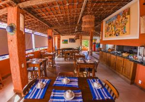 a restaurant with tables and chairs and a kitchen at Pousada Aconchego do Porto in Porto De Galinhas