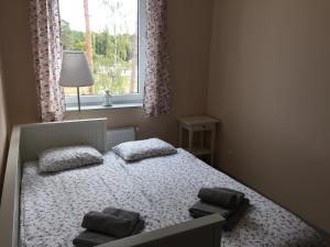 a bedroom with a bed with two pillows and a window at Apartament Malinowy Pogorzelica in Pogorzelica