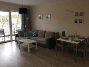 a living room with a couch and a table at Apartament Malinowy Pogorzelica in Pogorzelica