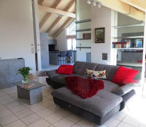 a living room with a gray couch and red pillows at Ferienwohnung bei Maly in Sulzberg