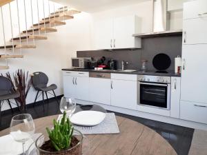 a kitchen with white cabinets and a table and a staircase at Casa Muro in Friedrichshafen