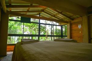 um quarto com uma cama e uma grande janela em Rancho Tierra Alta em Jarabacoa