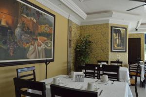 a dining room with tables and chairs and a painting on the wall at hotel villa magna poza rica in Poza Rica de Hidalgo