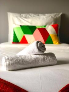 uma toalha numa cama com uma almofada colorida em Gamboa Surf Apartment em Peniche