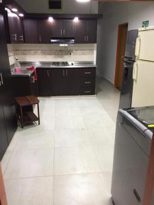 a kitchen with a white tile floor and black appliances at casa hostal las palmeras in Guatapé