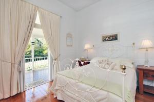 a bedroom with a white bed and a balcony at Mango Hill Farm in Peachester
