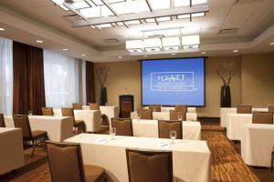 une salle de conférence avec des tables et des chaises blanches et un écran dans l'établissement Hyatt Palm Springs, à Palm Springs