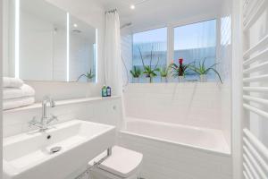 a white bathroom with a sink and a tub and a window at The Nook Tower Bridge in London +18 photos