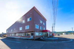 un grand bâtiment brun situé sur le côté d'une rue dans l'établissement Minshuku Nihonkai, à Ishikari