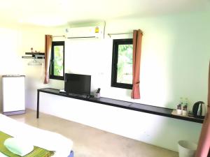 a room with a counter with a television and two windows at Wanlapa Farmstay in Ban Khok Krathiam