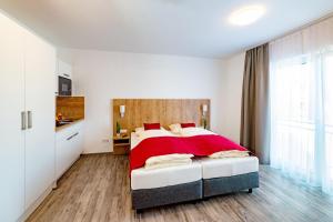 sypialnia z dużym łóżkiem i czerwonym kocem w obiekcie Boardinghaus Bayerwaldpark w mieście Landshut