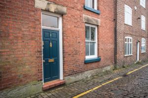 une porte bleue sur le côté d'un bâtiment en briques dans l'établissement The Little St Apartment, à Macclesfield
