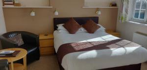 um quarto de hotel com uma cama e uma cadeira em Penryn Guest House, ensuite rooms, free parking and free wifi em Stratford-upon-Avon