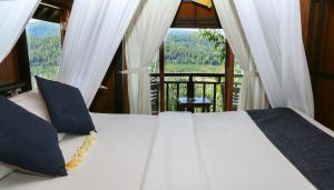 a bedroom with a bed and a large window at Bali Rahayu Homestay in Munduk
