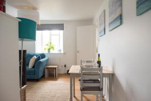 a living room with a table and a blue couch at Pebbles in Lyme Regis