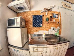a kitchen with a sink and a microwave and a refrigerator at 秘密基地 NO's ARROW ノーズアロー in Onna +24 photos