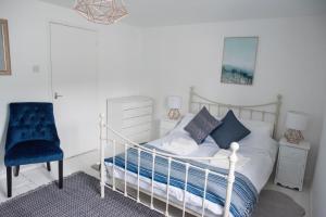 ein Schlafzimmer mit einem weißen Bett und einem blauen Stuhl in der Unterkunft Pebbles in Lyme Regis