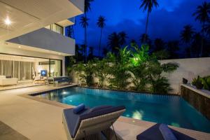 a villa with a swimming pool at night at Baan Siri Varee in Mae Nam